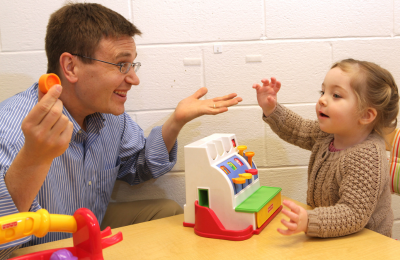 Image of a white man playing with a toy cash register with a young girl 